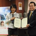 ユンナさん(左)とともに任命書を掲げる冬柴国交相