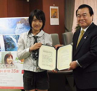ユンナさん(左)とともに任命書を掲げる冬柴国交相