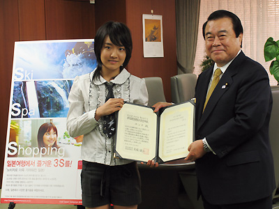 ユンナさん(左)とともに任命書を掲げる冬柴国交相