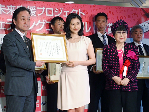 表彰式で撮影に応じる左から大町市の西沢課長、菊川さん、選定委員の桂由美さん