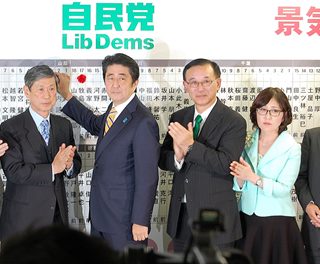 公示前の勢力をほぼ維持し、笑顔で当選のバラをつける安倍首相ら（12月14日夜、自民党本部）