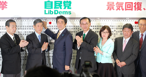 公示前の勢力をほぼ維持し、笑顔で当選のバラをつける安倍首相ら（12月14日夜、自民党本部）