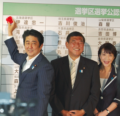 自民党本部の開票センターで当選者の名前に笑顔で花をつける安倍晋三総裁（首相）。 中央は石破茂幹事長、右端は高市早苗政調会長＝21日夜