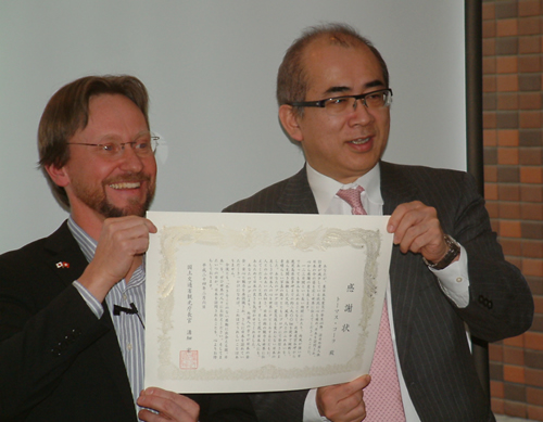 溝畑長官(右)とともに感謝状を披露するトーマスさん